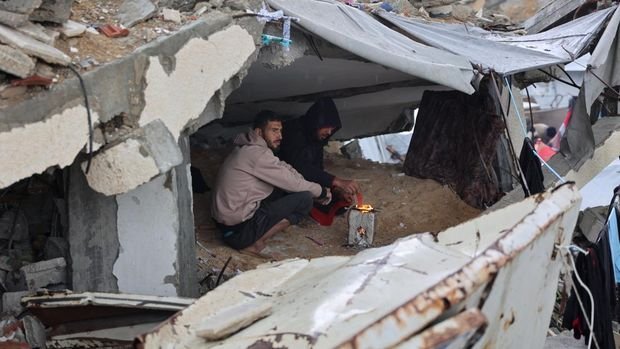 A displaced Palestinians clears water from his tent at a makeshift camp during a storm in Gaza City on December 31, 2024, amid the continuing war between Israel and the militant Hamas group. (Photo by Omar AL-QATTAA / AFP)